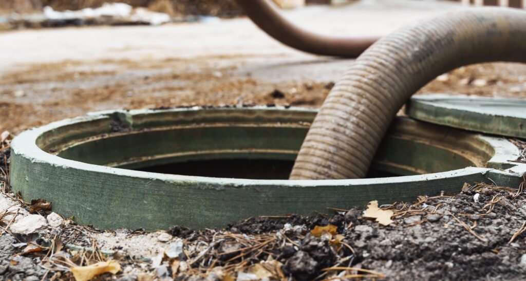 Pump hose lowered into an open tank during septic system services near Prescott, AZ.